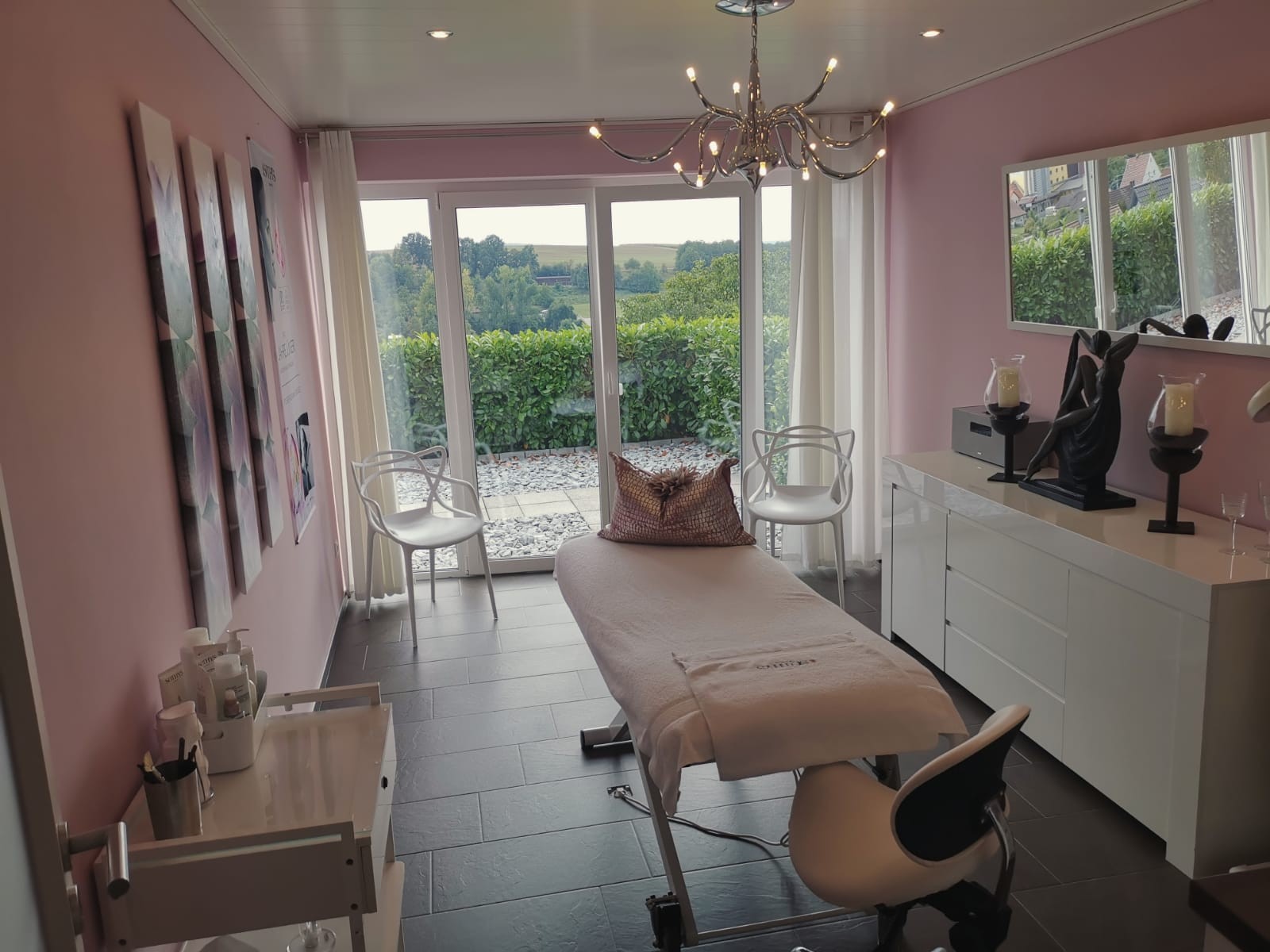 Kosmetik-Behandlungsraum in Rosé mit großer Glasfront und Blick ins Grüne